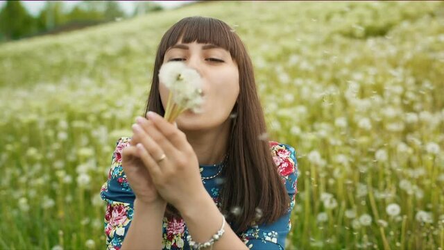 Smiling Woman Blow on a Dandelion