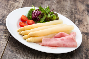 White asparagus with salad and ham on wooden background
