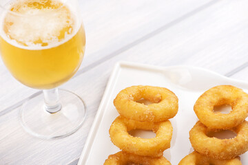 Close-up of a plate of squid a la romana next to a beer on white wooden table. Food squids.