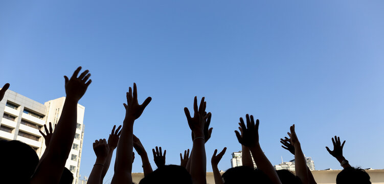 community initiative or volunteering concept, hands of group of people in the blue sky, silhouette