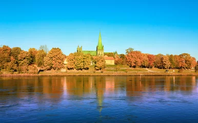 Fotobehang Fall in Trondheim, Norway. The view of the Cathedral Nidarosdomen and the river Nidelva in the sunny autumn day © liramaigums