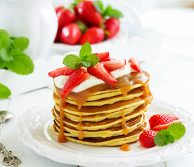 Pancakes with caramel and strawberries for breakfast.