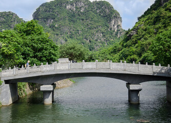 Fototapeta na wymiar Male tourist on the stone bridge with river and mountain in Vietnam.