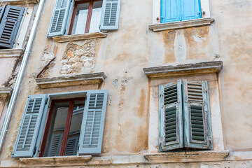 Fototapeta na wymiar Old windows with blue shutters in the old house. Vintage background