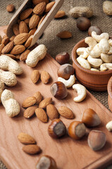 Almonds, cashew and hazelnuts in wooden bowls on wooden and burlap, sack background