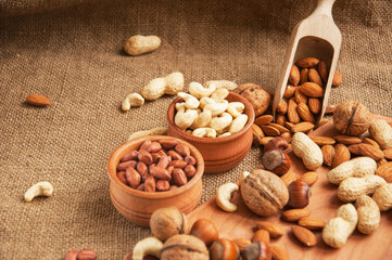 Almonds, cashew, walnuts and hazelnuts in wooden bowls on wooden and burlap, sack background
