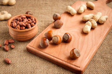  peanut,  hazelnuts in wooden bowls on wooden and burlap, sack background