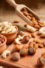 Almonds, cashew and hazelnuts in wooden bowls on wooden and burlap, sack background