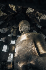 Stone buddha statue inside a pagoda and light shines onto the statue