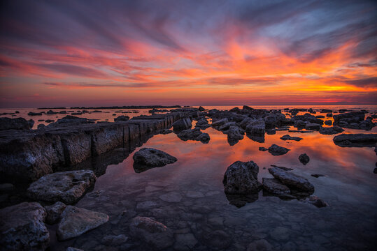 red sunset with ancient rocks platform on sea