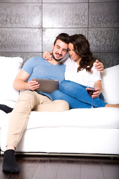 Young couple using a Tablet PC together on the Sofa at home