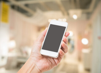 Hand holding empty screen mobile phone with abstract blurred interior background