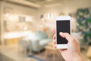Hand holding empty screen mobile phone with abstract blurred interior background