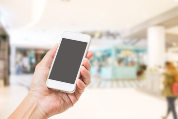 Fototapeta na wymiar Hands holding mobile phone with blurred image of shopping mall