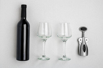 Red wine bottle, glasses and corkscrew over white background. Top view with copy space