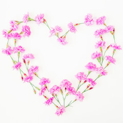 Love symbol made of pink flowers on white background. Flat lay, top view.