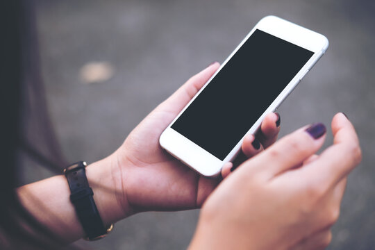 Mockup image of hand holding white mobile phone with blank black screen with blur gray color background