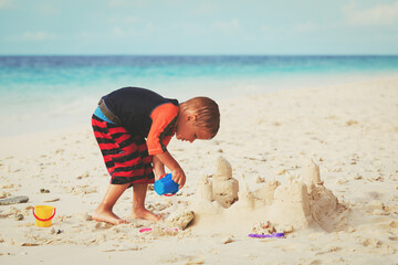 little boy building sand castle on beach