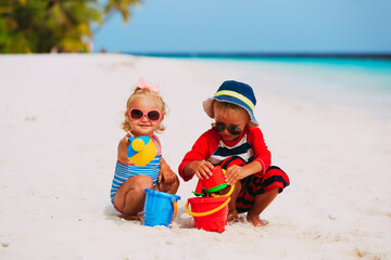 happy little boy and girl play with sand on beach