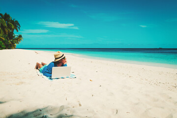 man with laptop on tropical beach
