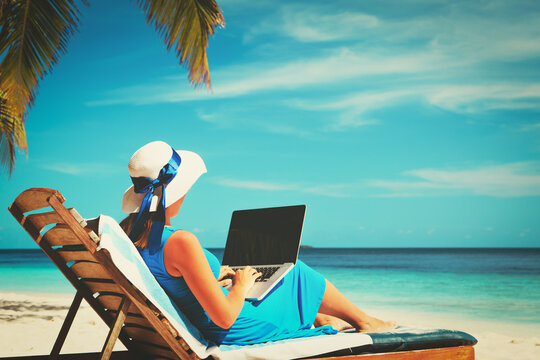 young woman with laptop on beach