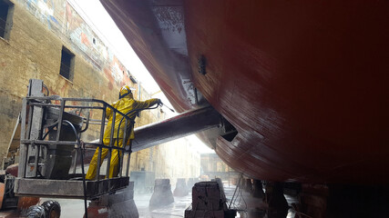 worker washing ship hull at drydock