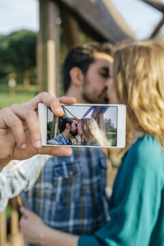 Kissing young couple taking selfie with smartphone