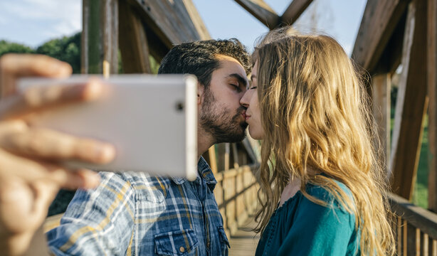 Couple in love taking selfie with smartphone while kissing