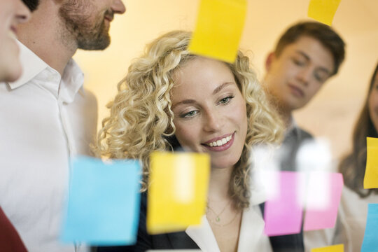 Business people discussing in front of glass screen with sticky notes