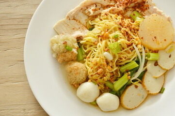 dried spicy Chinese egg noodles topping fish and shrimp ball with slice boiled pork on plate