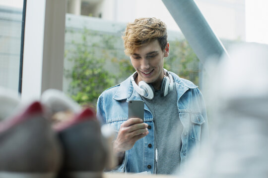 Young man taking a photo of shoes through a window