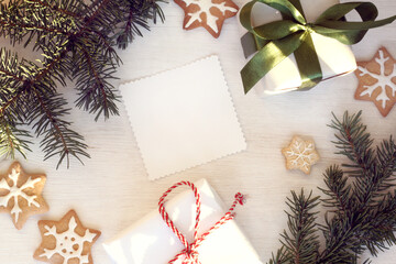 Christmas background for congratulations/ flat layout with festive gifts and figured biscuits on the table with fir branches top view