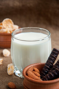 A glass of milk with almond nuts, corn flakes, chocolates,  on sacking background