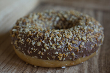 Sweet donut with chocolate and nuts on wood plate