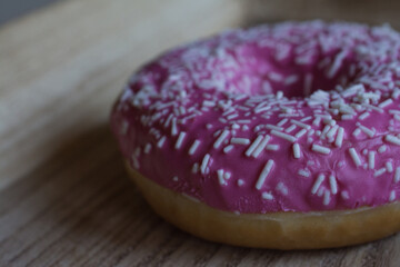 Sweet pink donut on wood plate