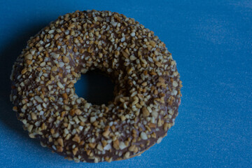 Sweet donut with chocolate and nuts on blue wood plate