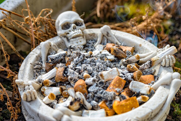 Skull ashtray with many cigarettes in this