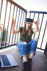 Beautiful young woman enjoying virtual reality at her apartment terrace. 