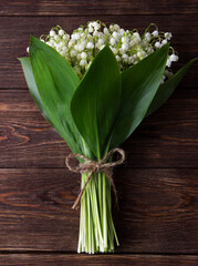 Lily of the valley on dark wooden background. Lily of the valley bouquet. Space for text.