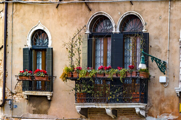 Fototapeta na wymiar old balconies in a Venice colorful building with red flowers