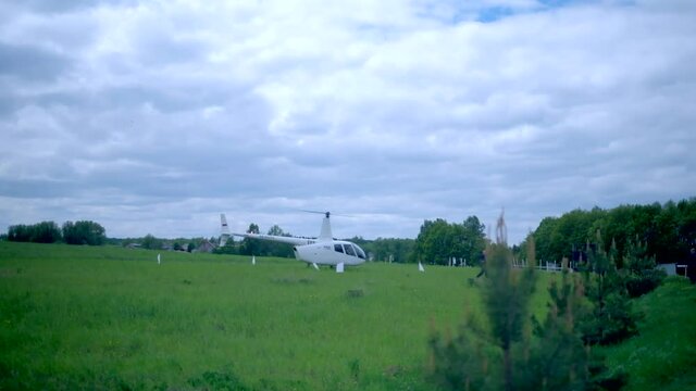 The helicopter lands on a green field, the blades rotate hd