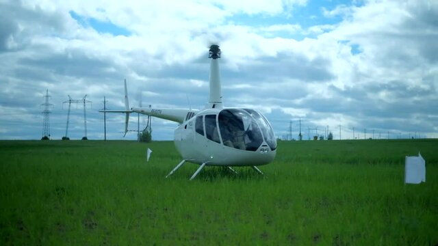 The helicopter lands on a green field, the blades rotate hd