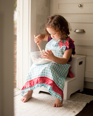 Young girl in apron baking cookies