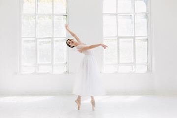 Obraz premium Young and incredibly beautiful ballerina is posing and dancing in a white studio