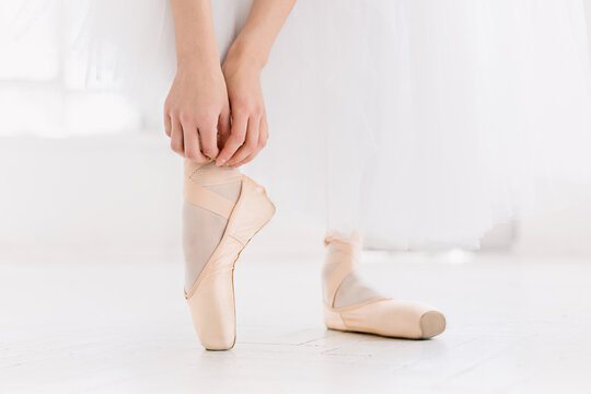 Young ballerina dancing, closeup on legs and shoes, standing in pointe position.