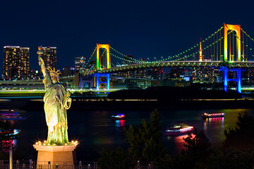 Rainbow Bridge and the Statue of Liberty at night with the bridge lit up in rainbow lights, Tokyo, Japan - obrazy, fototapety, plakaty