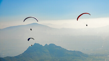 Paragliding above mountain valley. Paragliders fly over the peaks