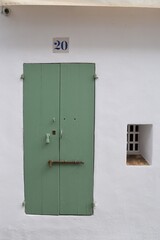 Hoher Eingang zu Haus Nummer 20, grüne Holztür mit Eisenriegel, kleines Fenster rechts neben der Tür