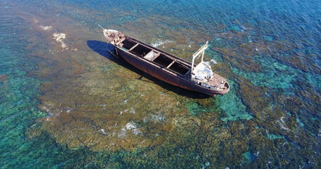 Fototapeta premium Beautiful seascape with old big, broken, rusty boat near the coast of Peyia, Cyprus. Ship graveyard. Famous landmark in the Mediterranean sea.