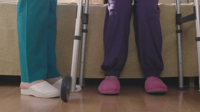 Caregiver helping senior woman getting up from bed and walk with a walker. Home or hospice nursing and assistance concept. 4K footage at 60fps.